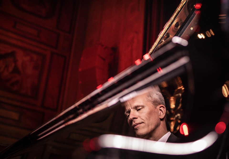 Man som sitter vid ett piano. Fotografi.